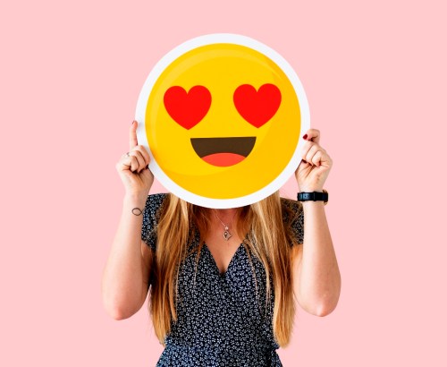 Cheerful woman holding emoticon icon